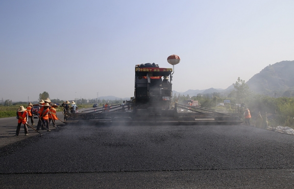 2019年8月，宜春經(jīng)開區(qū)S311路面攤鋪現(xiàn)場，工友們輔助路面兩側的分料、補窩等作業(yè)