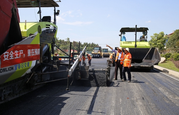 攤鋪機(jī)、壓路機(jī)等設(shè)備緊張有序運(yùn)行，高達(dá)170℃的瀝青混合料炙烤著公路人